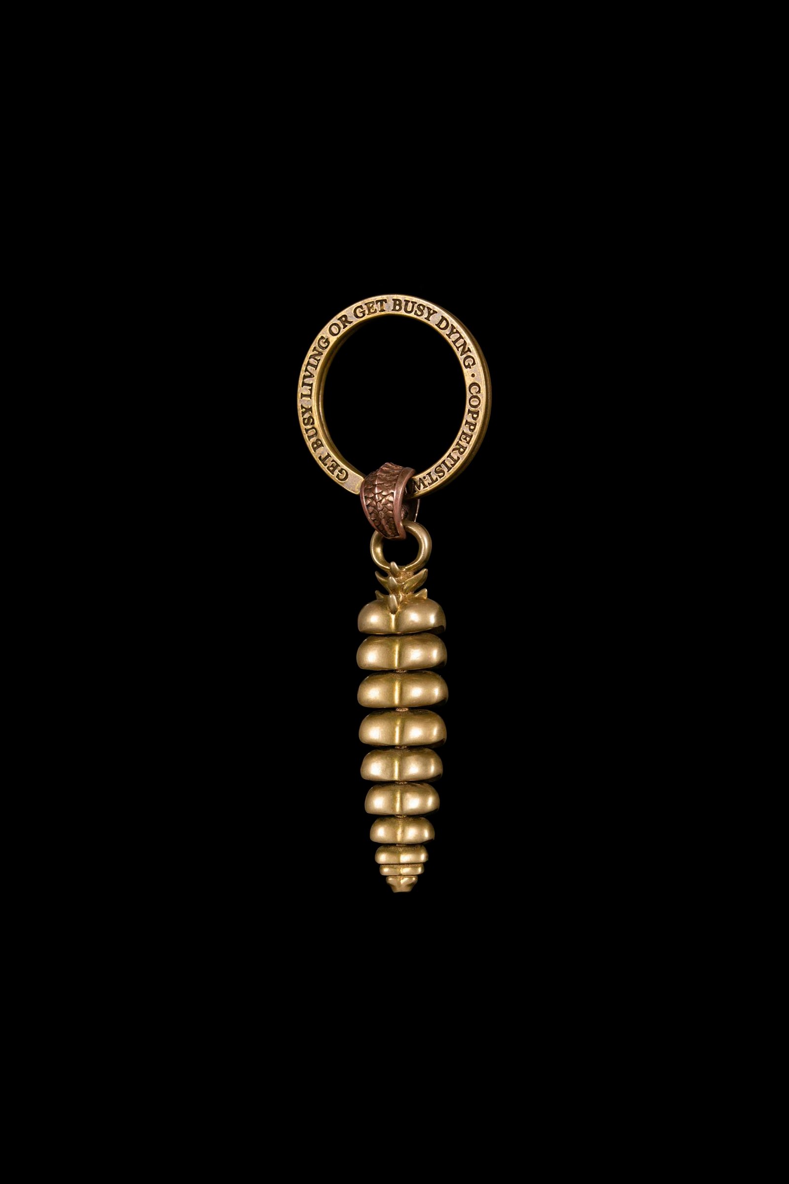 Artistic golden key ring against a black background showcasing intricate design.