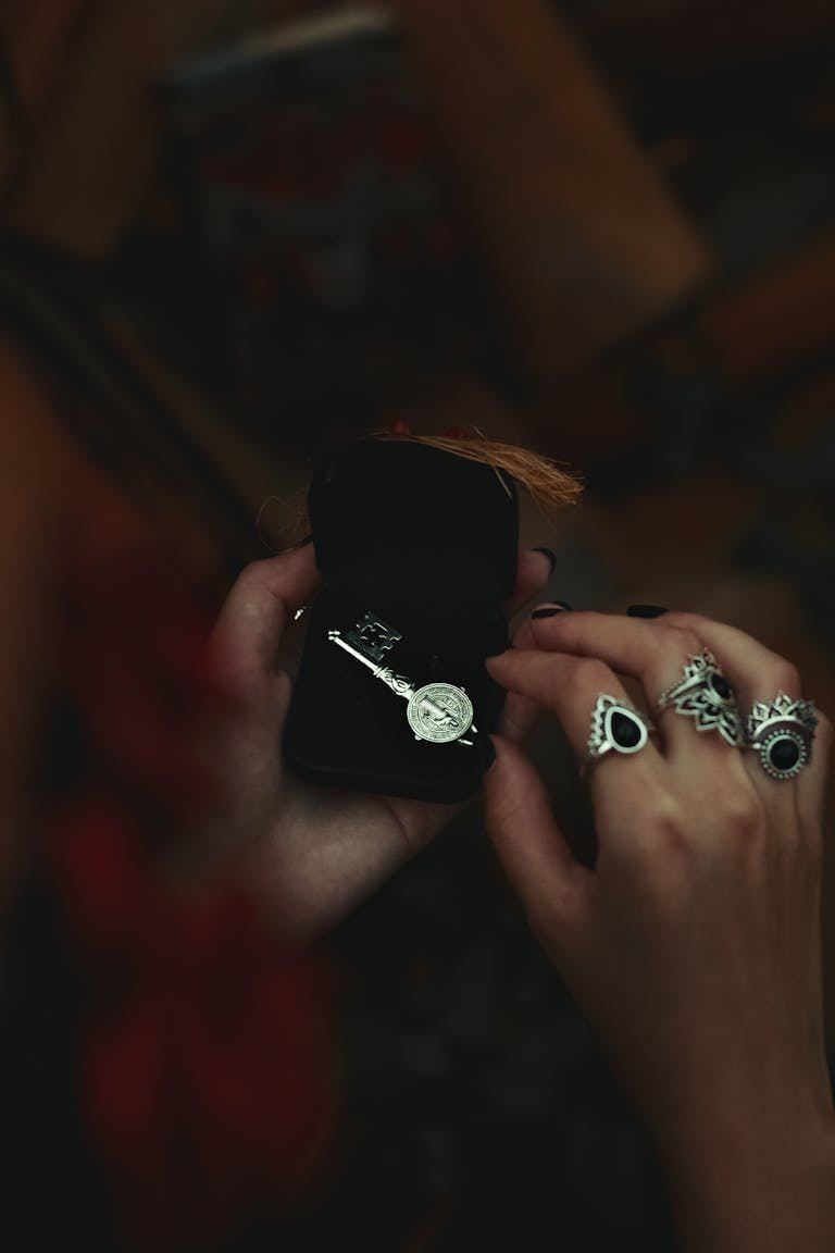 Close-up of a hand holding a jewelry box with intricate rings and key ring.