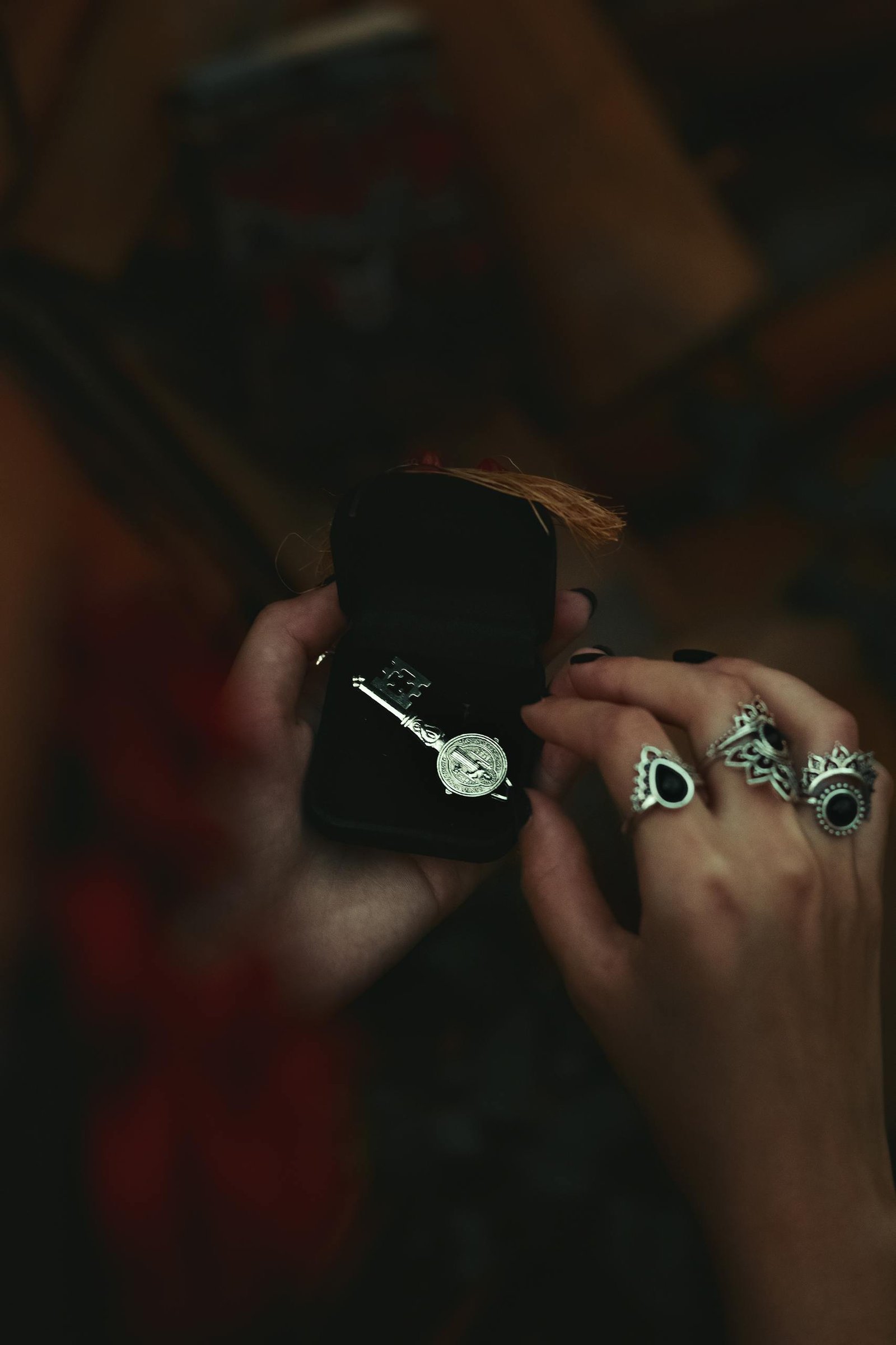 Close-up of a hand holding a jewelry box with intricate rings and key ring.